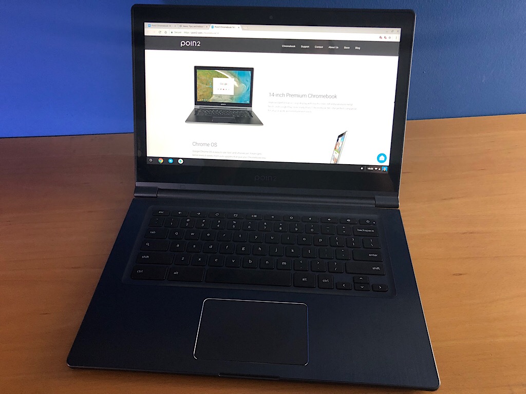 Photo of the Poin2 Chromebook 2 taken on a wood table, with a blue background wall.
