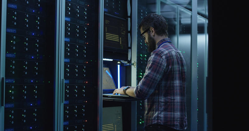 Un specialist IT cu barbă care setează serverele în centrul de date