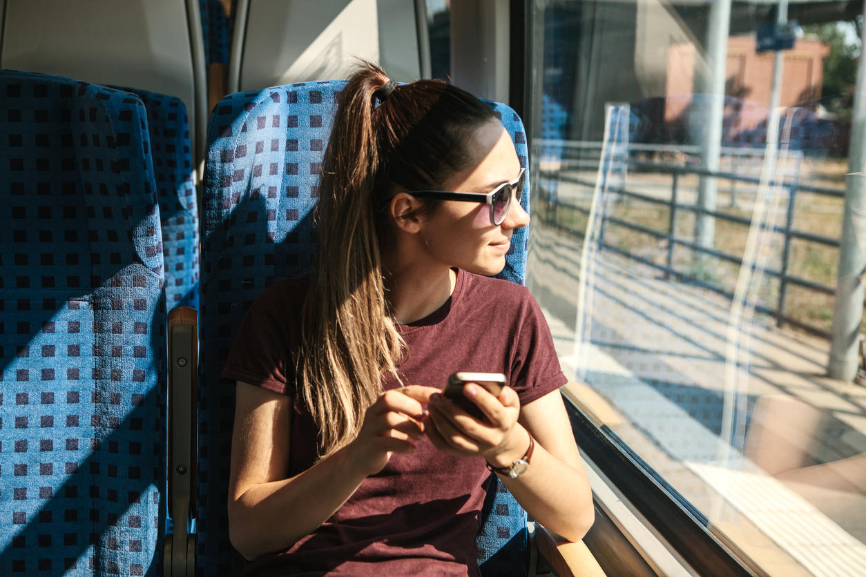 A tourist on the train uses a mobile phone.