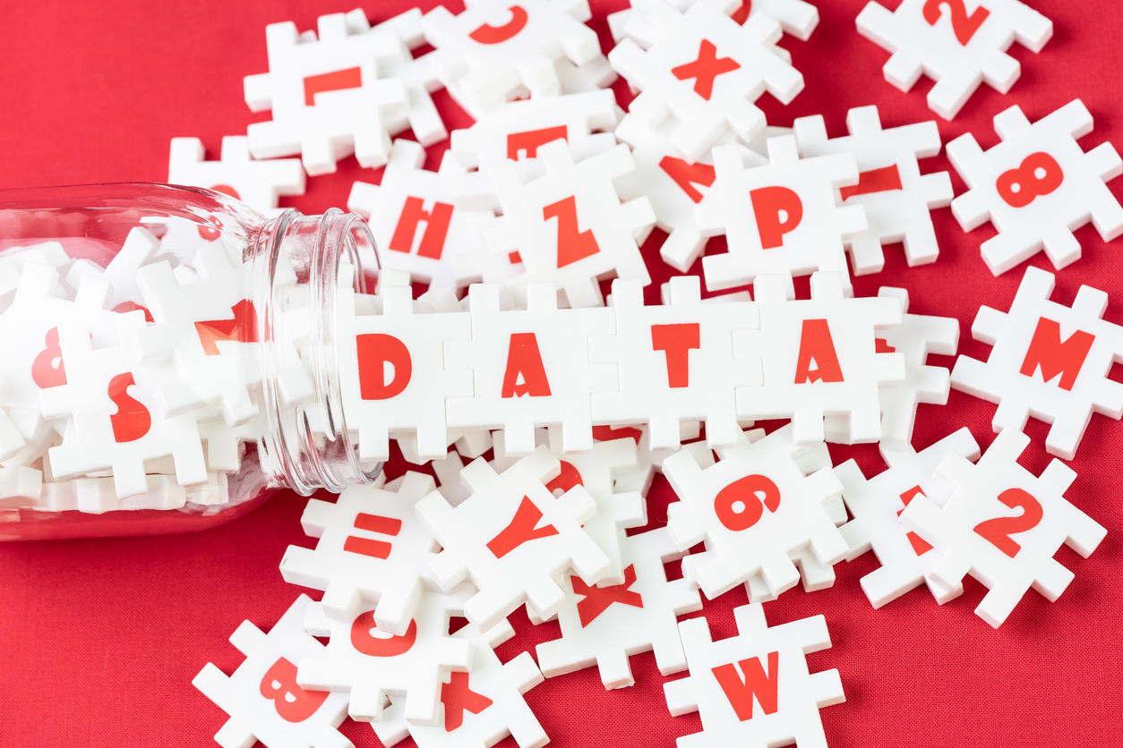 Big data analysis, unstructured database processing metaphor, large volume of  white puzzle jigsaws with alphabets pouring from bottle combine word DATA on red fabric background with copy space