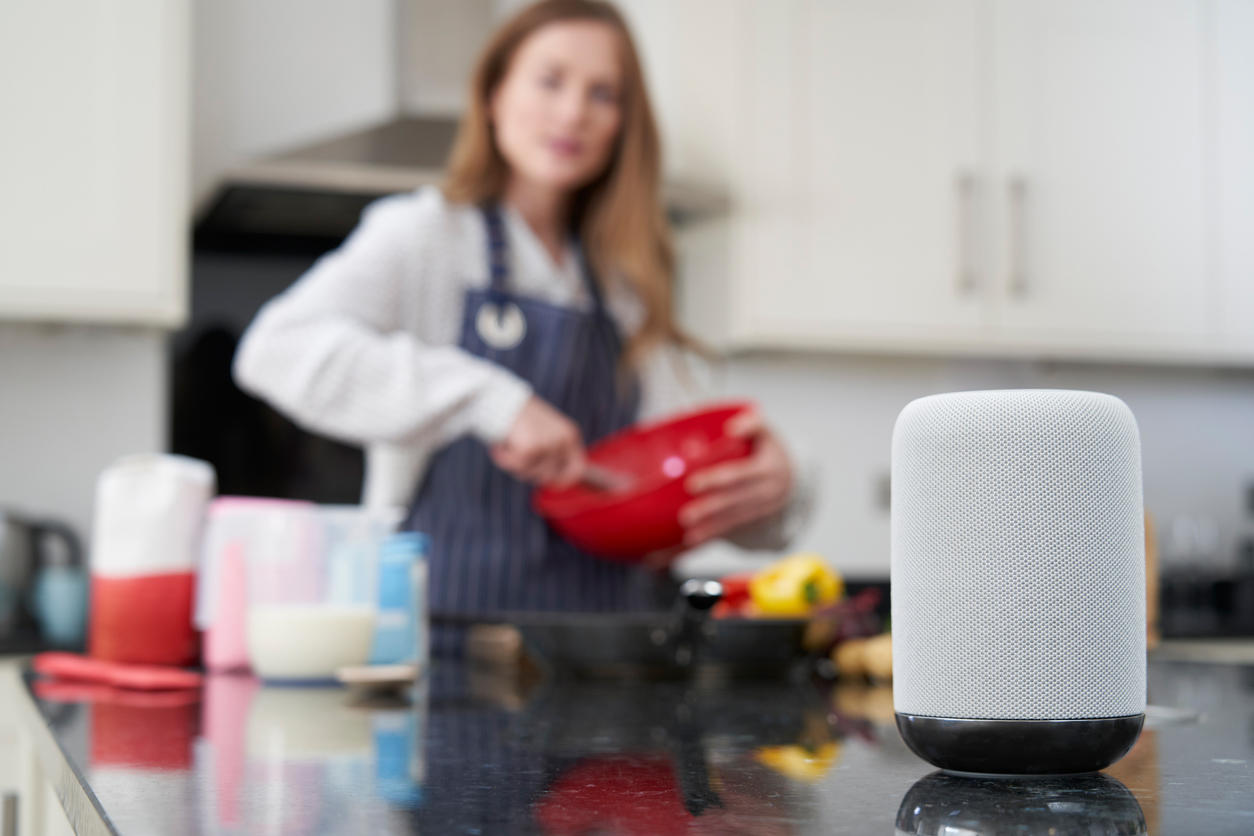 Woman Preparing Meal At Home Asking Digital Assistant Question