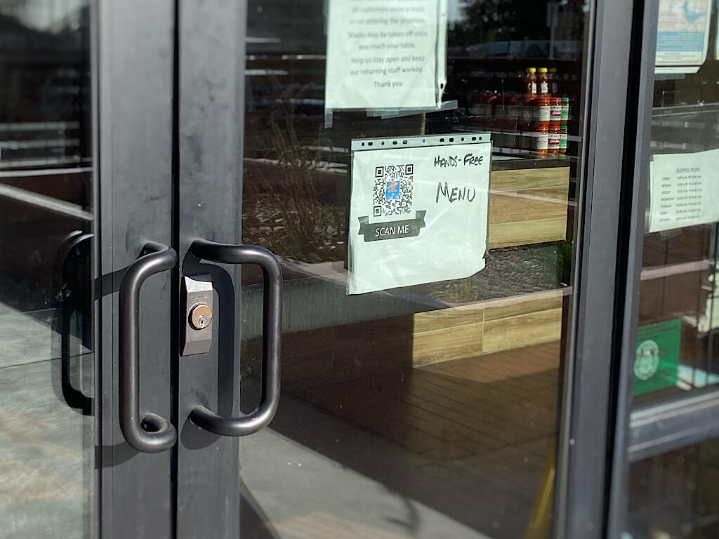 Photo of a QR code on a restaurant's front door (with note that says scan for menu)