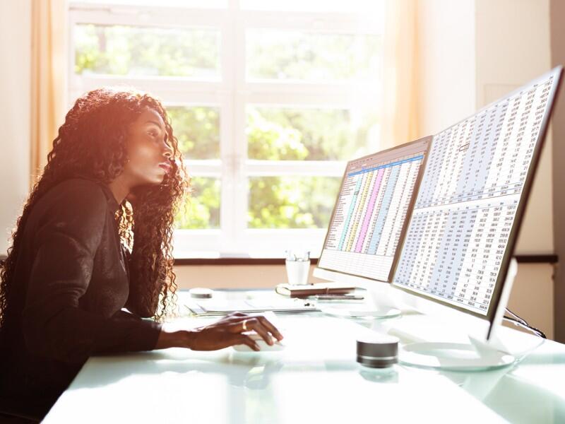 Black woman looking at spreadsheets on screens