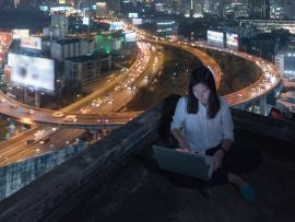 Asian woman work late by laptop on rooftop at night