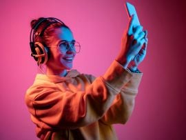Fashion pretty woman with headphones listening to music over neon background