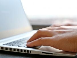 man's hands typing on laptop
