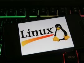 Closeup of mobile phone screen with logo lettering of linux on computer keyboard