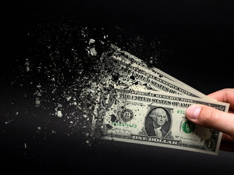 Inflation, dollar hyperinflation with black background. One dollar bill is sprayed in the hand of a man on a black background.