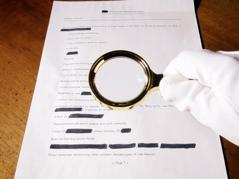 A spy looking at a (fake) secret document with a magnifying lens.