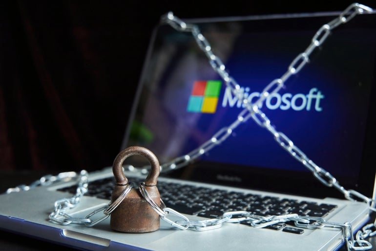 Krasnodar, Russia - March, 04, 2022; A large heavy rusty lock with a chain on a laptop with the Microsoft logo. Sanctions and blocking and access restrictions.