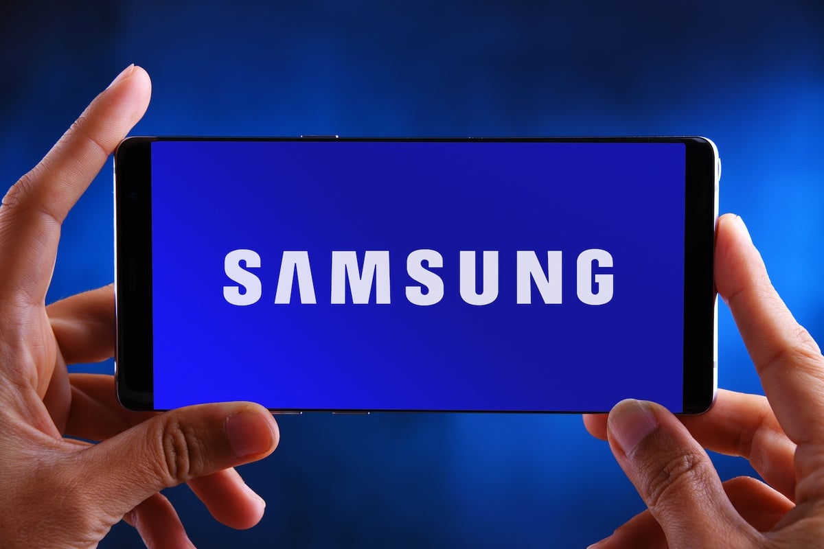 Hands holding smartphone displaying logo of Samsung.