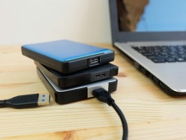 Many Colorful Portable external hard Drives USB3.0 connect to laptop computer on wooden background