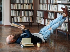 Bearded hipster man relax and reading book lies on the floor