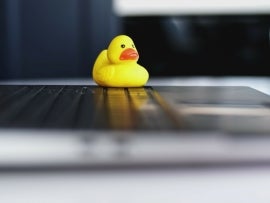 Yellow Rubber Duck Sitting on Laptop As Focus Aid For Software Engineer during Code Debugging