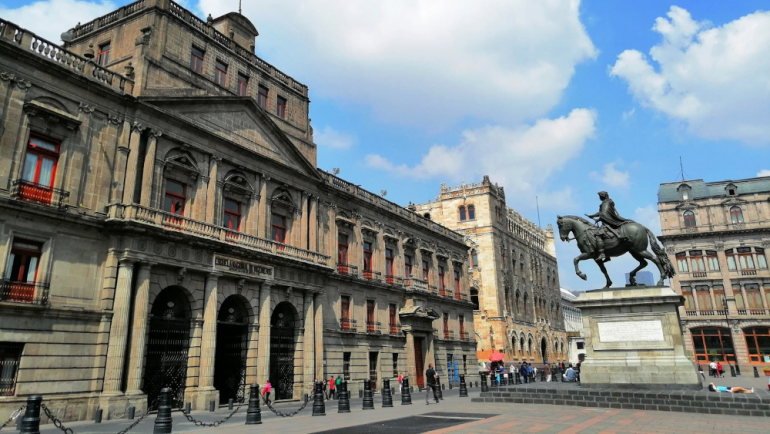 a building and statue along Tacuba Street in South America
