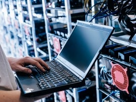 IT specialist working on computer in bitcoin and crypto currency mining farm.