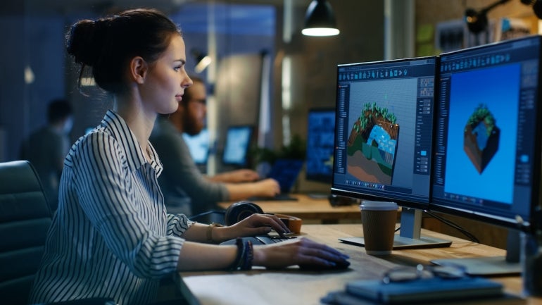 Female Game Developer Works on a Level Design on Her Personal Computer with Two Displays. She works in a Creative Office Space.