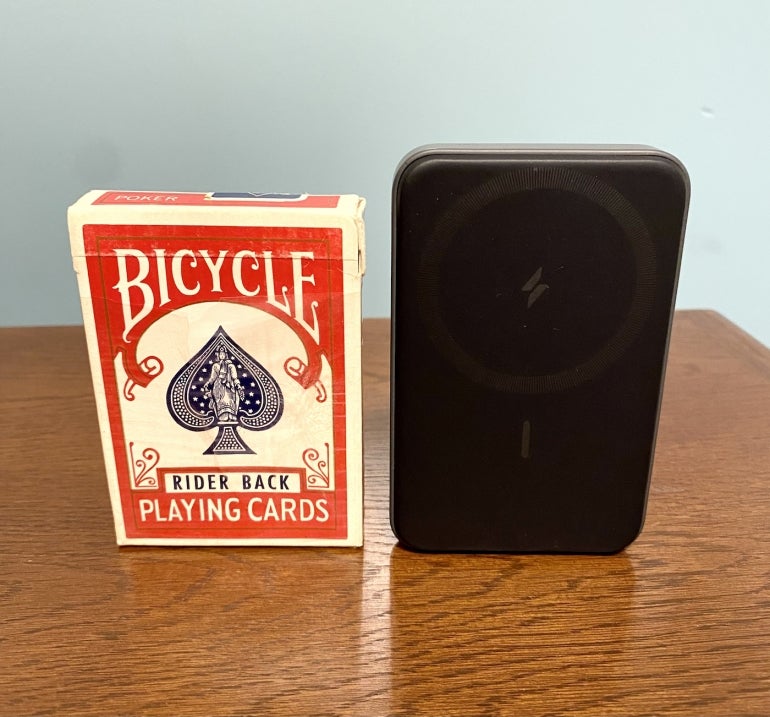 A MagGo charger next to a similarly sized pack of cards on a table.