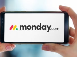 Hands holding smartphone displaying logo of monday.com