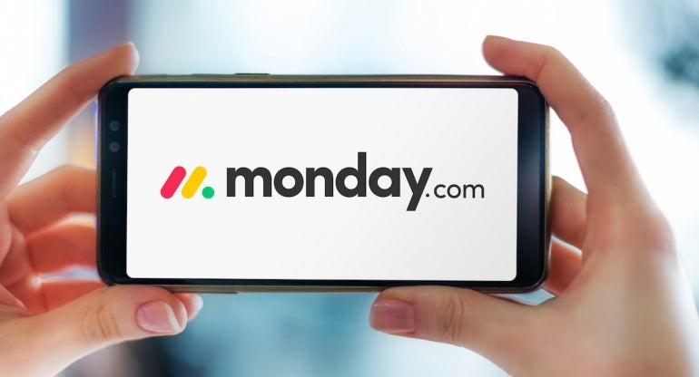 Hands holding smartphone displaying logo of monday work management