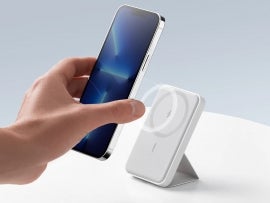 Hand placing an iphone 13 on a Anker MagGo charger.