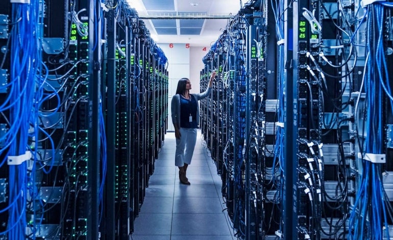 woman standing in between a bunch of server racks