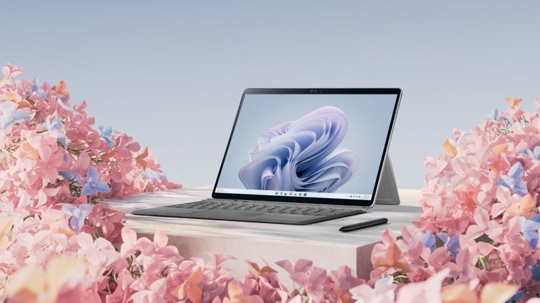 a Surface Pro 9 surrounded by pink and blue flowers