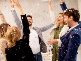 Group of business people celebrating and toasting with confetti falling in the office
