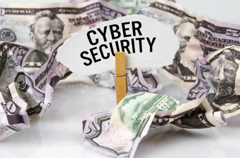 There are dollars on the table and there is a clothespin with paper on which it is written - CYBER SECURITY