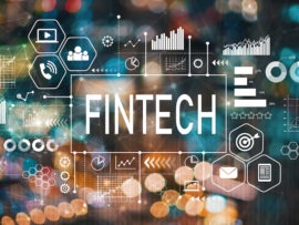 The word Fintech with finance symbols over a blurry background.