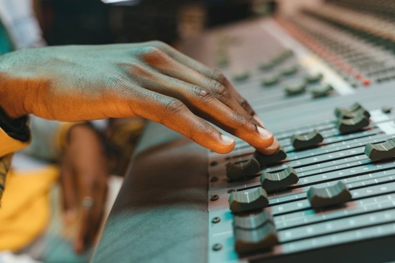 A hand moving a dial on an audio mixer.