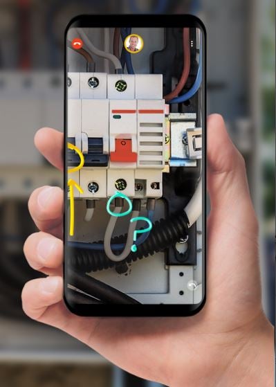 Someone holding a phone with an image of a machine that has annotations on the screen indicating certain parts.