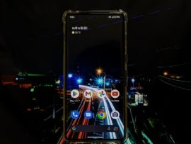 A smart phone with several apps displayed. The phone's background looks like a night sky and a multicolored, lit street; this imagery is also visible in the image background.