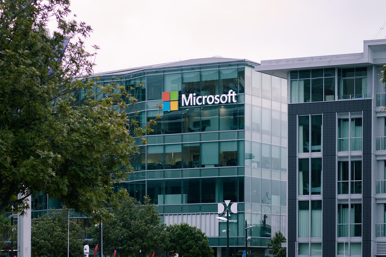 Microsoft logo is prominently displayed on the outside of a multi-story glass building.