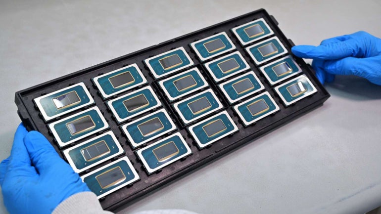 A tray of Intel Core Ultra Processors held up by a gloved worker.
