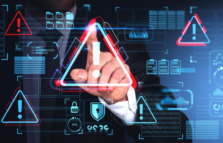 Main d'homme d'affaires utilisant l'interface de cybersécurité d'alerte de malware avec icône d'avertissement triangulaire sur l'écran tactile sur fond bleu.