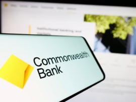 Smartphone with logo of company Commonwealth Bank of Australia (CBA) on screen in front of website.