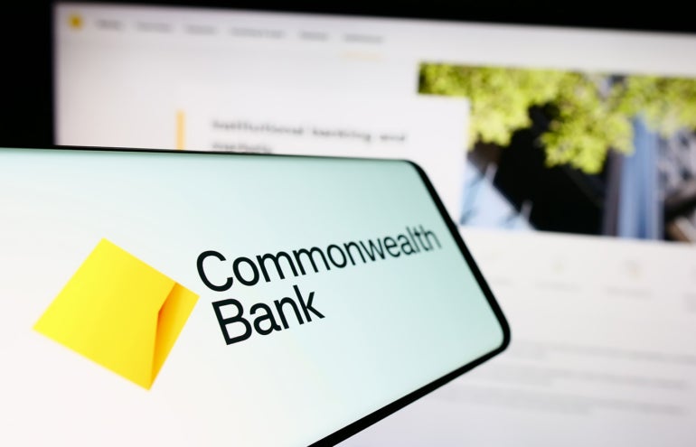 Smartphone with logo of company Commonwealth Bank of Australia (CBA) on screen in front of website.
